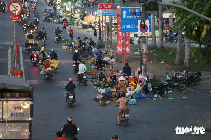 Bày bán rau, củ, quả... dưới lòng đường, đi ngược chiều trước chợ đầu mối Thủ Đức- Ảnh 1. Nhiều người dân lấn chiếm lòng đường quốc lộ 1, bày bán rau củ quả... tiềm ẩn nguy cơ tai nạn