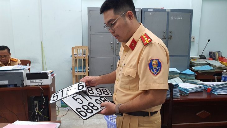 Cán bộ cảnh sát giao thông ở TP.HCM thu hồi biển số định danh - Ảnh: MINH HÒA Bộ Công an đề xuất mới quy chuẩn kỹ thuật quốc gia về biển số xe- Ảnh 1.